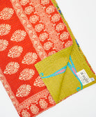 kantha quilt throw with a tag featuring the hand-stitched signature of the maker