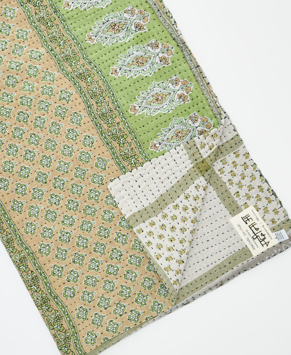 kantha quilt throw with a tag featuring the hand-stitched signature of the maker