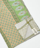 kantha quilt throw with a tag featuring the hand-stitched signature of the maker