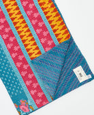 kantha quilt throw with a tag featuring the hand-stitched signature of the maker