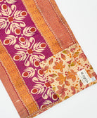 kantha quilt throw with a tag featuring the hand-stitched signature of the maker