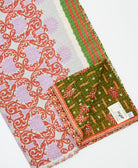 kantha quilt throw with a tag featuring the hand-stitched signature of the maker