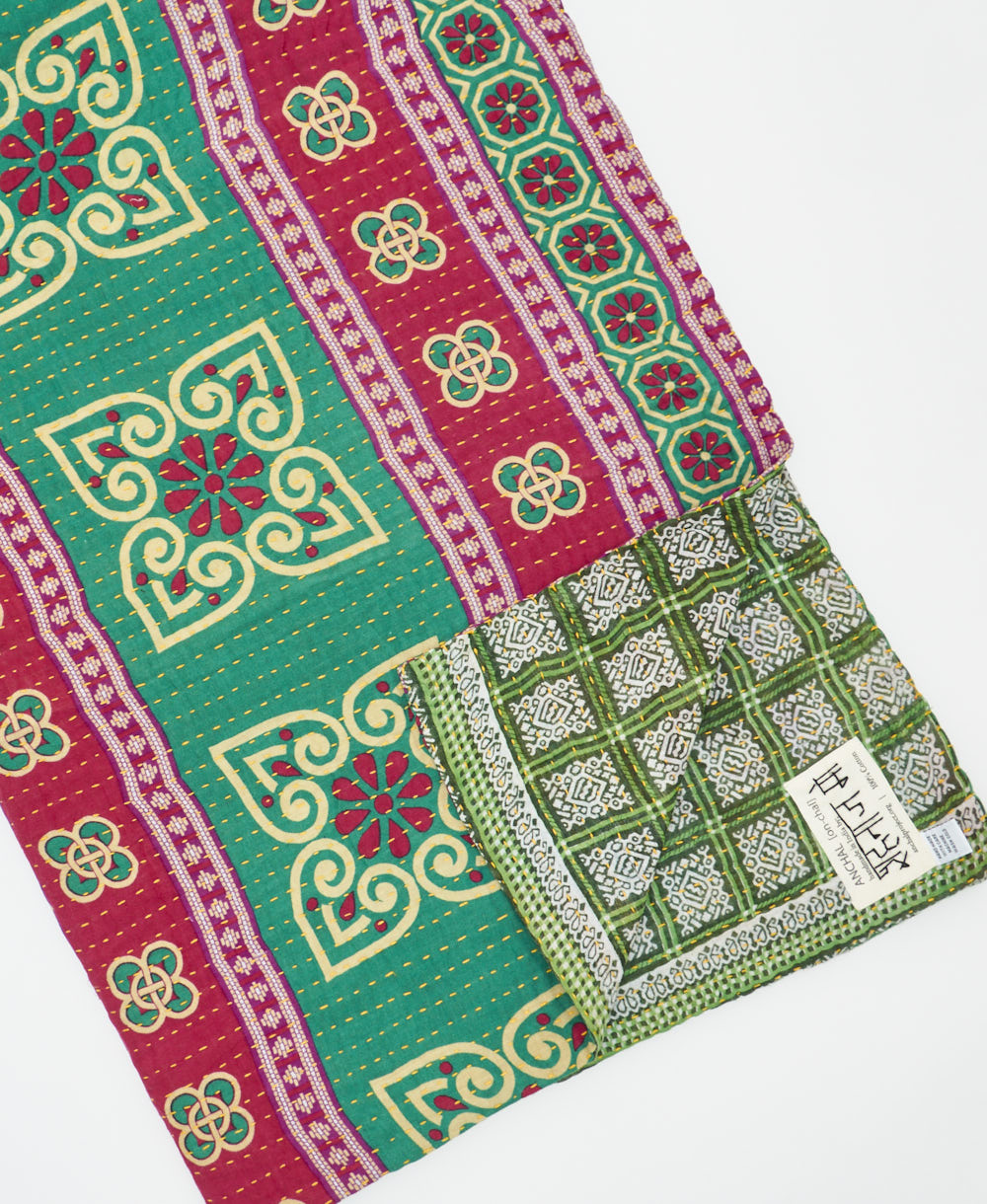 kantha quilt throw with a tag featuring the hand-stitched signature of the maker