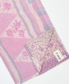 kantha quilt throw with a tag featuring the hand-stitched signature of the maker