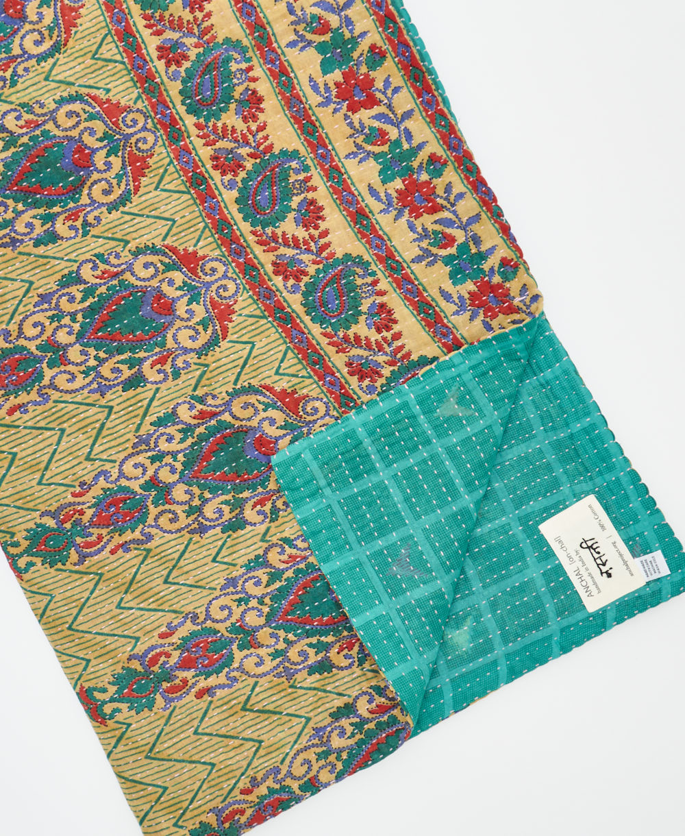 kantha quilt throw with a tag featuring the hand-stitched signature of the maker