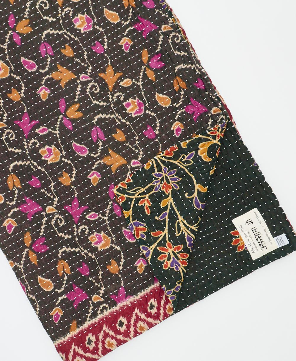 kantha quilt throw with a tag featuring the hand-stitched signature of the maker