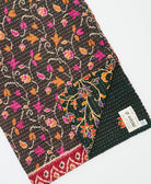 kantha quilt throw with a tag featuring the hand-stitched signature of the maker