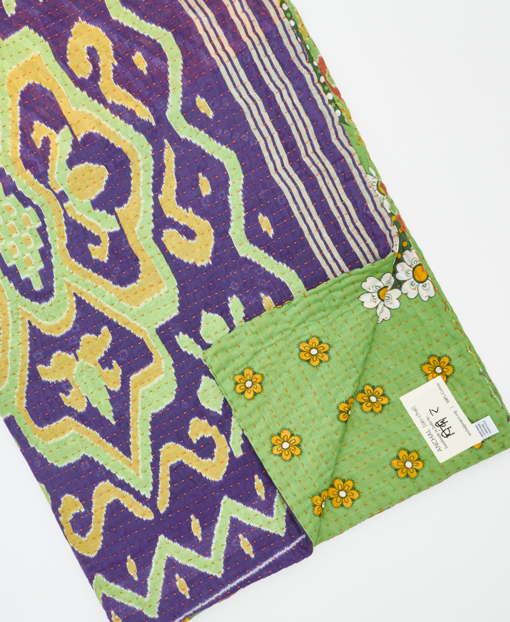 kantha quilt throw with a tag featuring the hand-stitched signature of the maker