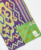 kantha quilt throw with a tag featuring the hand-stitched signature of the maker