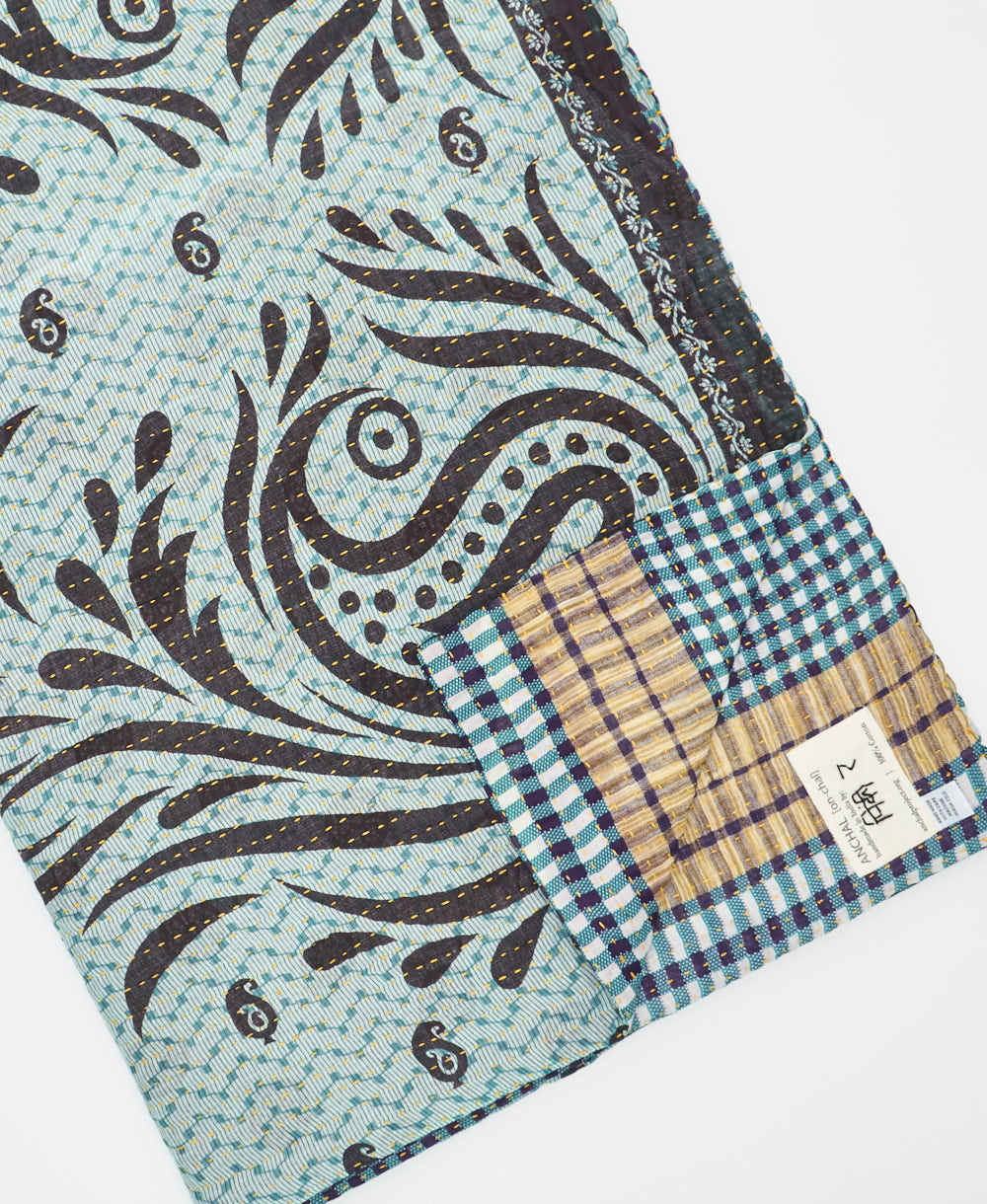 kantha quilt throw with a tag featuring the hand-stitched signature of the maker