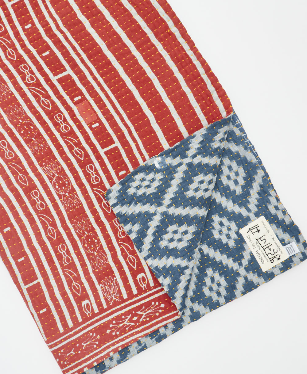 kantha quilt throw with a tag featuring the hand-stitched signature of the maker