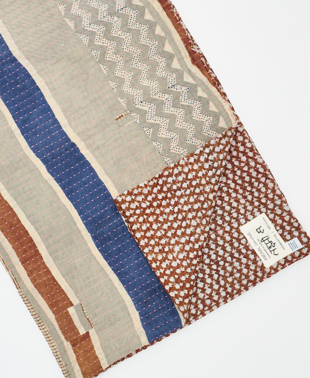 kantha quilt throw with a tag featuring the hand-stitched signature of the maker