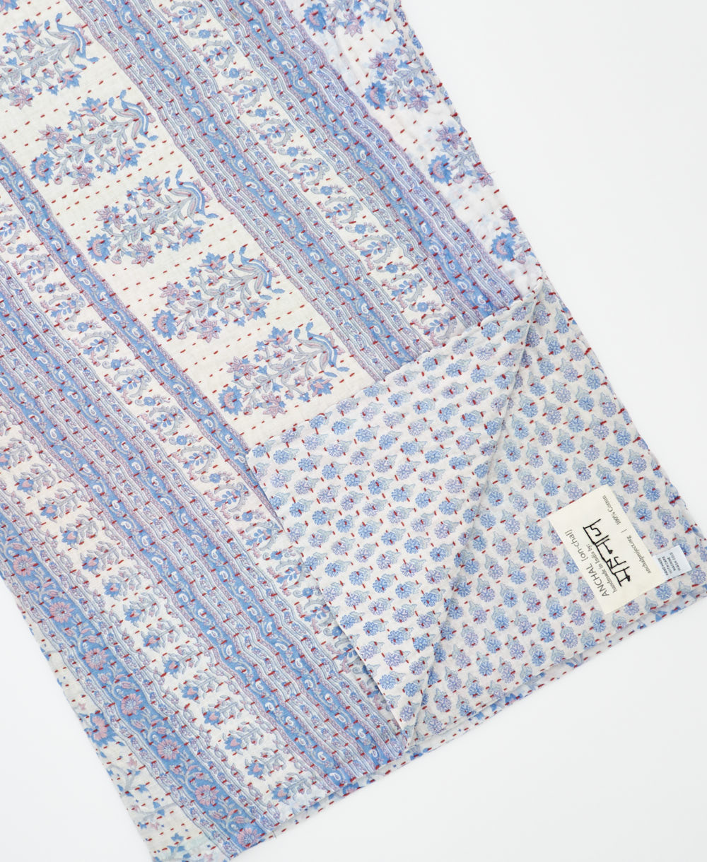 kantha quilt throw with a tag featuring the hand-stitched signature of the maker