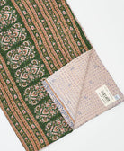 kantha quilt throw with a tag featuring the hand-stitched signature of the maker