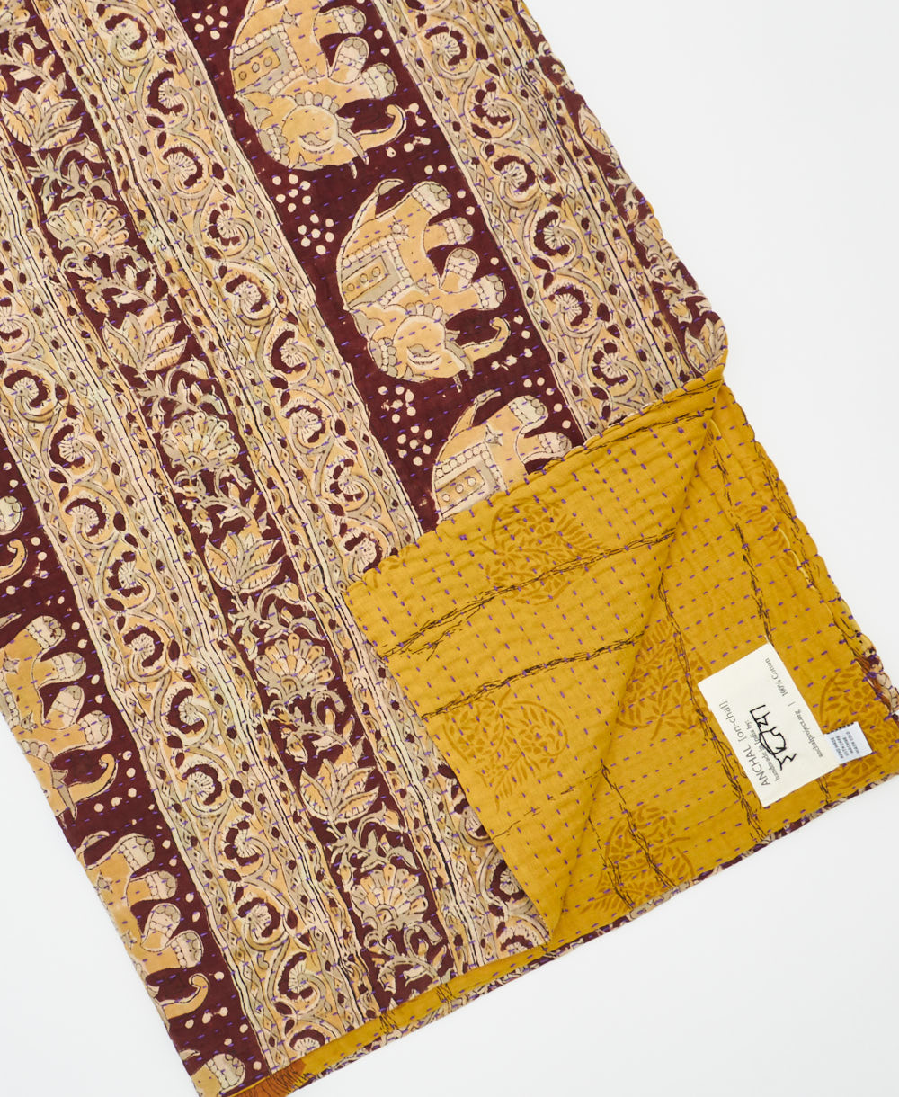 kantha quilt throw with a tag featuring the hand-stitched signature of the maker