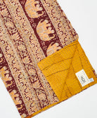kantha quilt throw with a tag featuring the hand-stitched signature of the maker