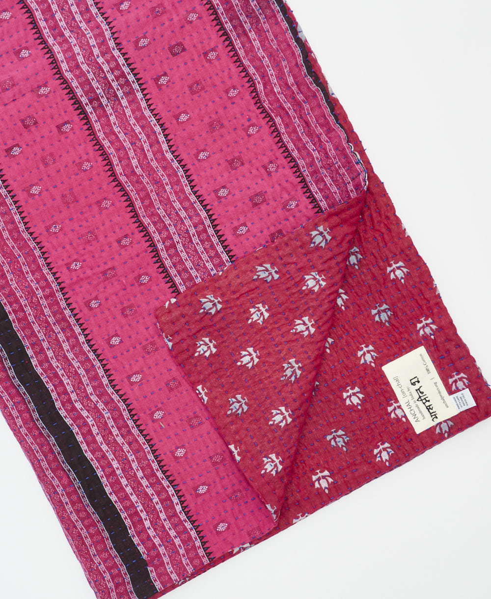 kantha quilt throw with a tag featuring the hand-stitched signature of the maker