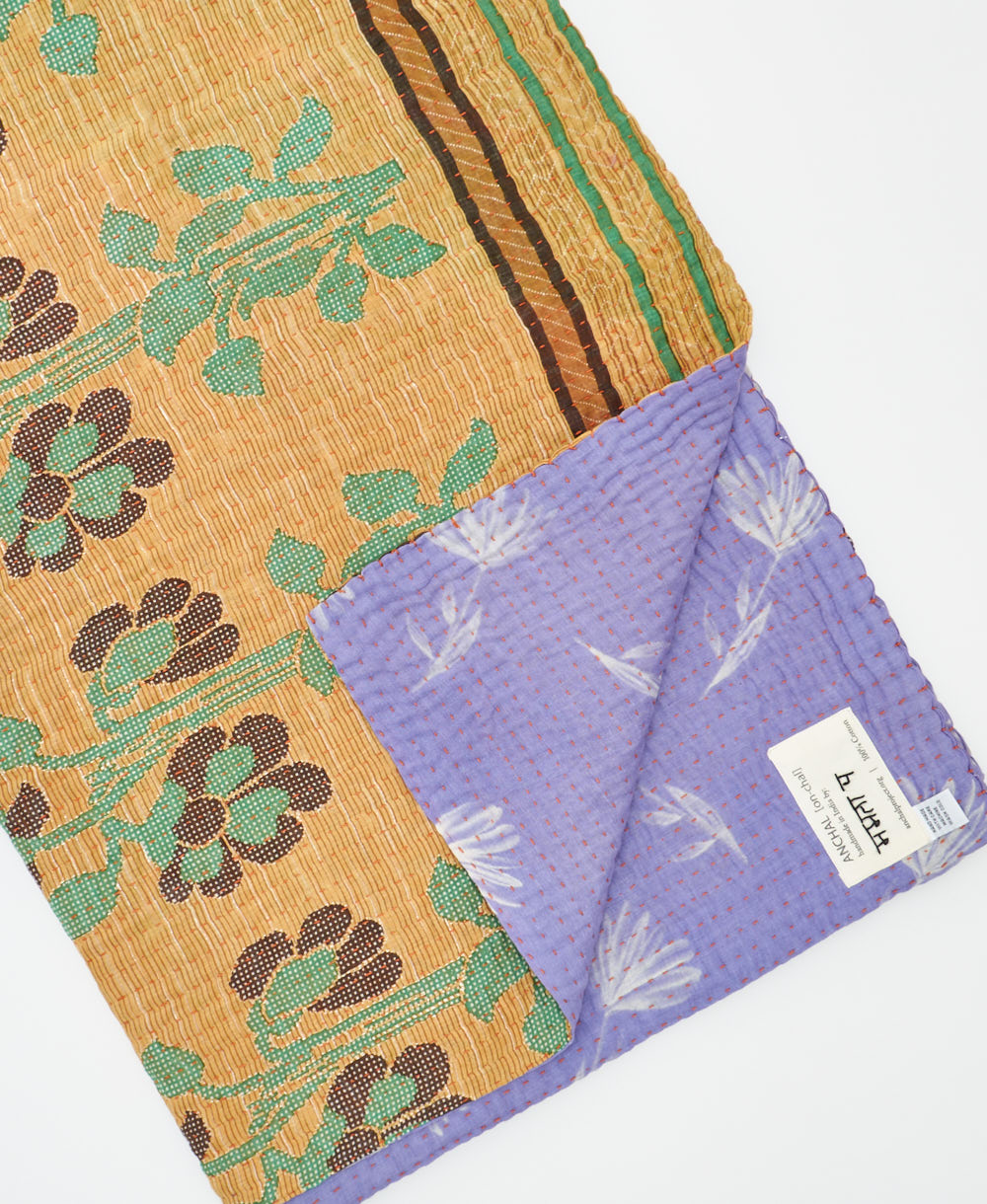 kantha quilt throw with a tag featuring the hand-stitched signature of the maker