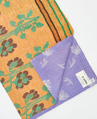 kantha quilt throw with a tag featuring the hand-stitched signature of the maker