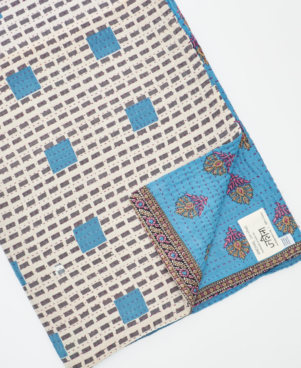 kantha quilt throw with a tag featuring the hand-stitched signature of the maker