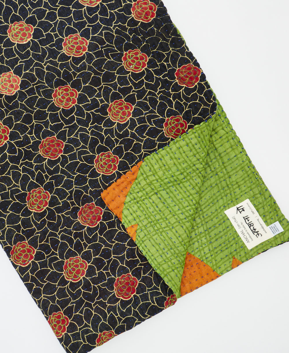 kantha quilt throw with a tag featuring the hand-stitched signature of the maker