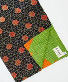 kantha quilt throw with a tag featuring the hand-stitched signature of the maker