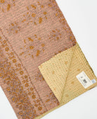 kantha quilt throw with a tag featuring the hand-stitched signature of the maker