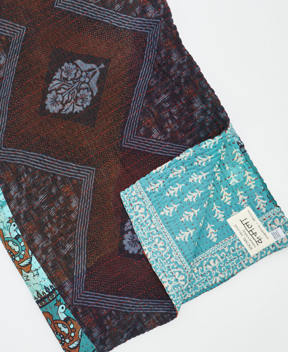 kantha quilt throw with a tag featuring the hand-stitched signature of the maker