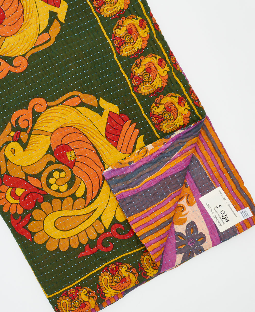 kantha quilt throw with a tag featuring the hand-stitched signature of the maker