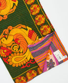 kantha quilt throw with a tag featuring the hand-stitched signature of the maker