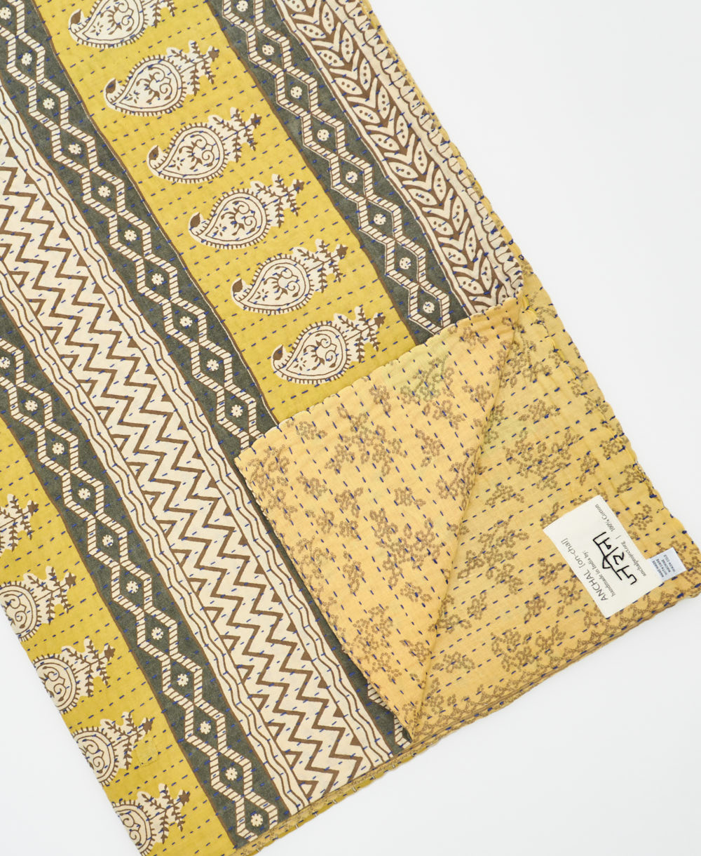 kantha quilt throw with a tag featuring the hand-stitched signature of the maker