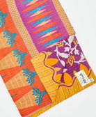 kantha quilt throw with a tag featuring the hand-stitched signature of the maker