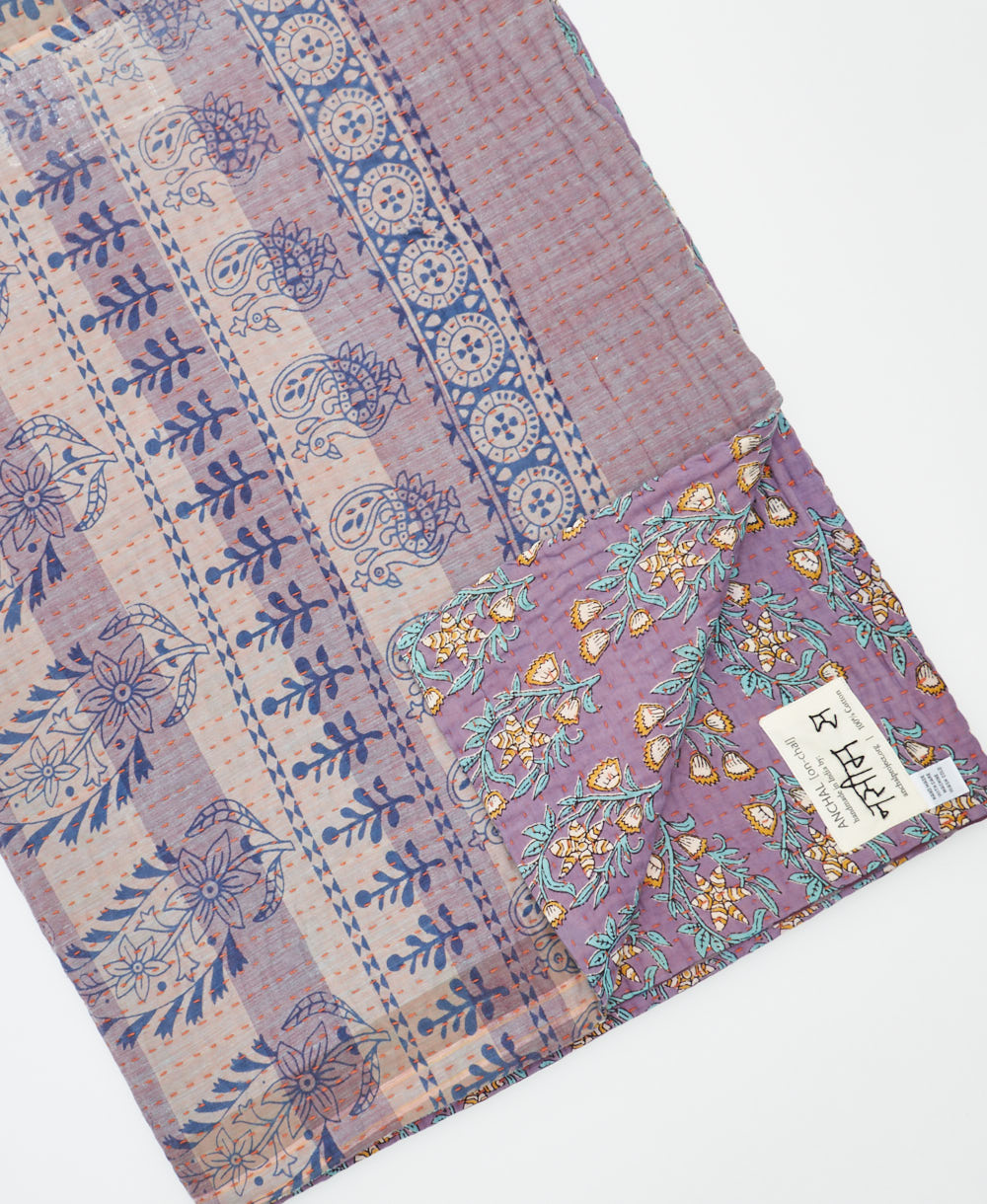kantha quilt throw with a tag featuring the hand-stitched signature of the maker