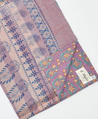 kantha quilt throw with a tag featuring the hand-stitched signature of the maker