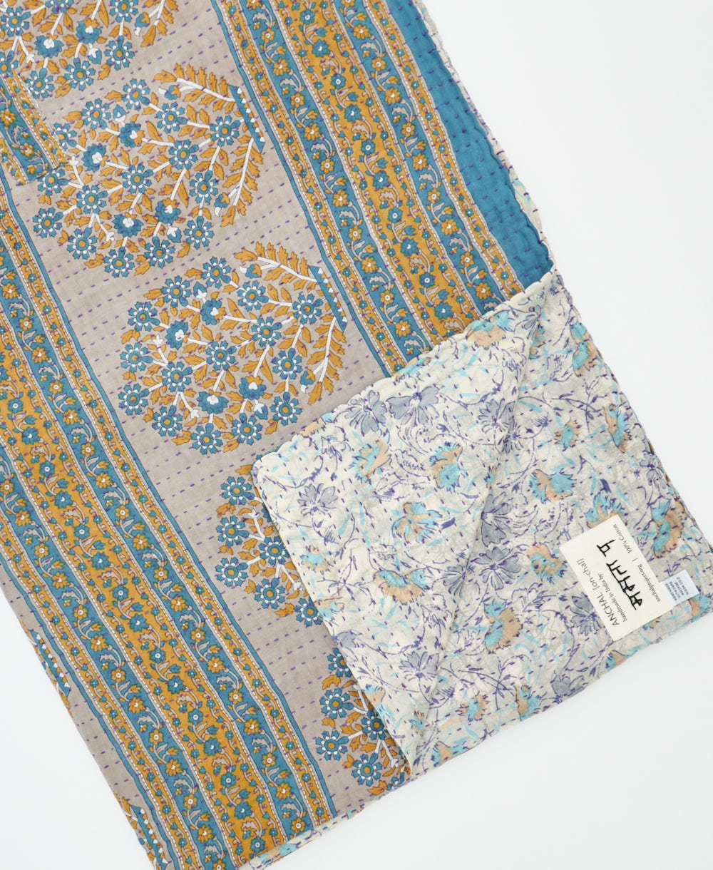 kantha quilt throw with a tag featuring the hand-stitched signature of the maker