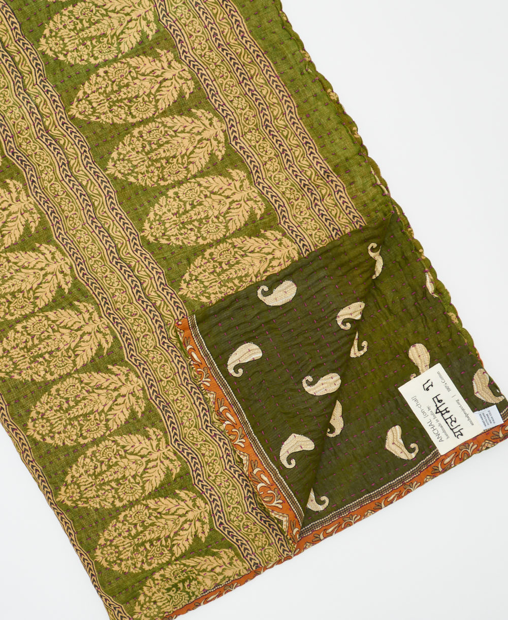 kantha quilt throw with a tag featuring the hand-stitched signature of the maker