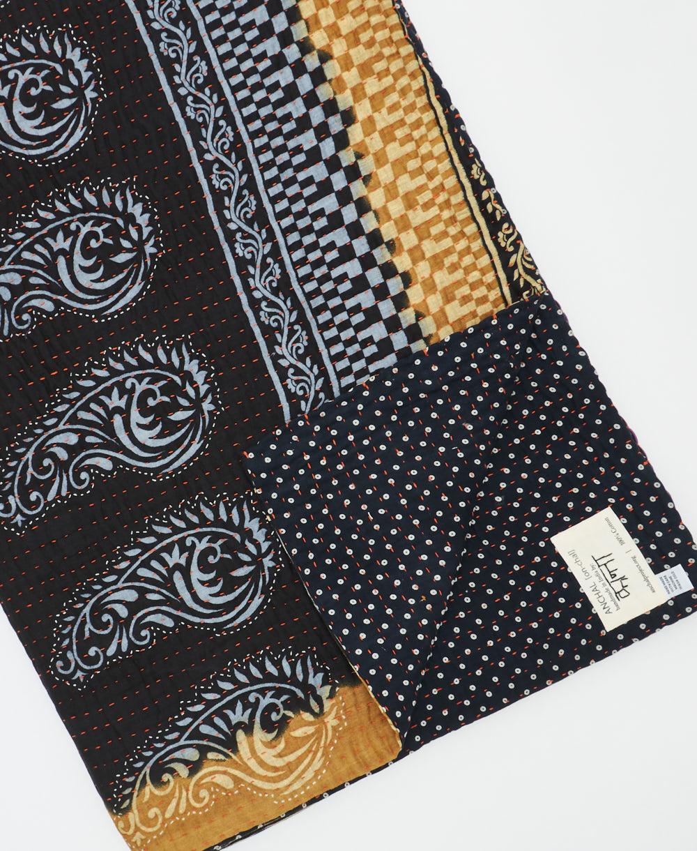 kantha quilt throw with a tag featuring the hand-stitched signature of the maker