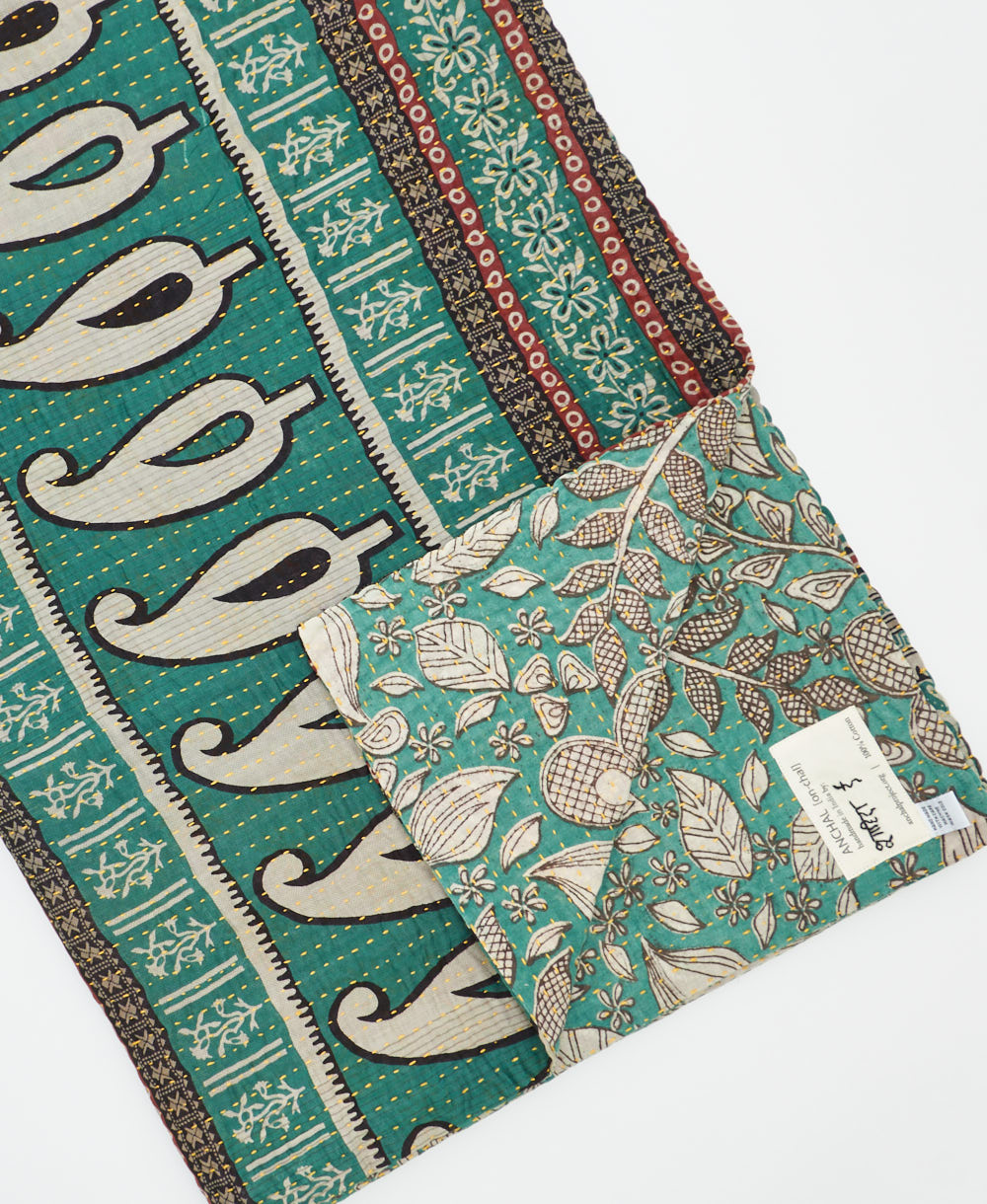 kantha quilt throw with a tag featuring the hand-stitched signature of the maker