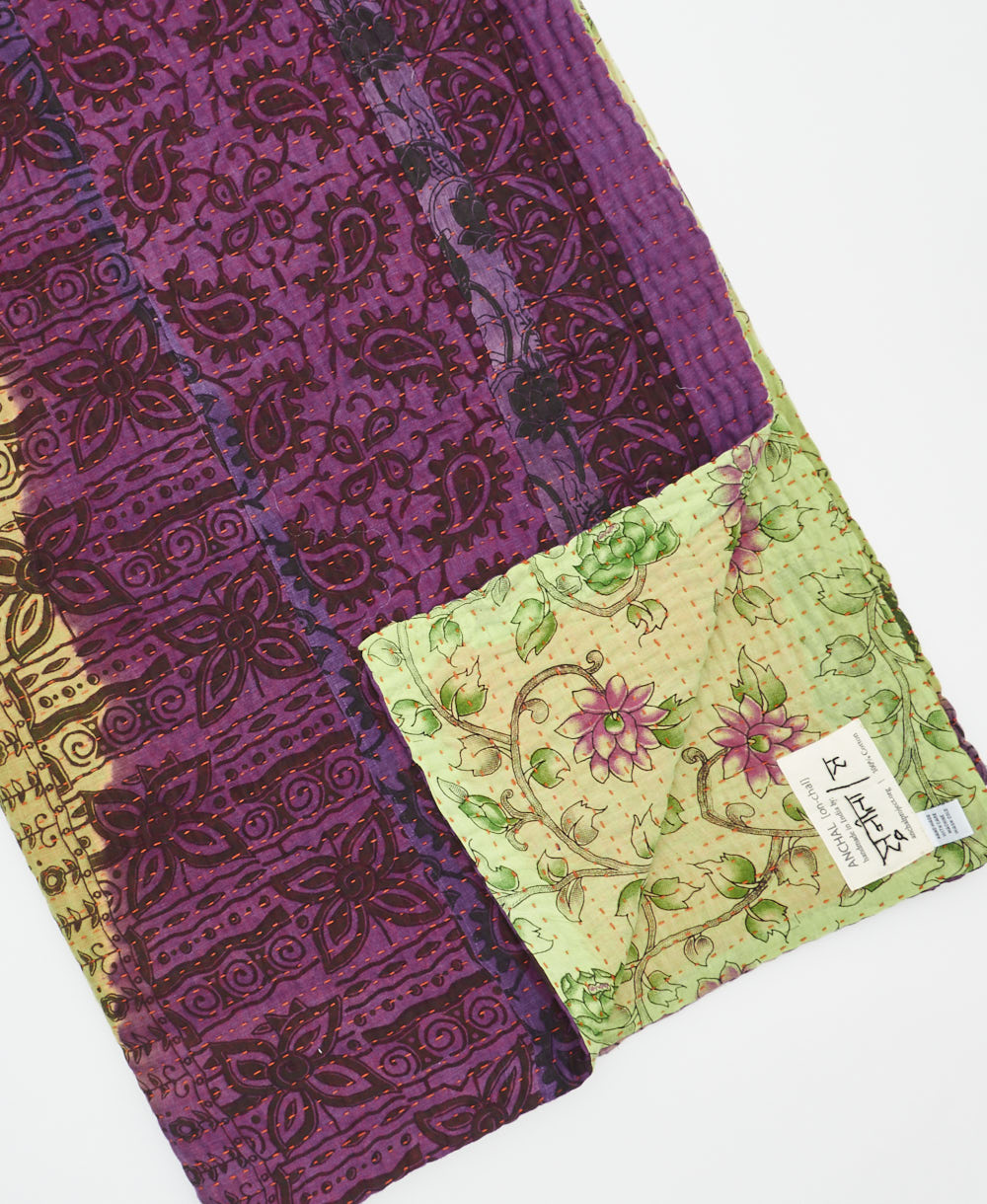 kantha quilt throw with a tag featuring the hand-stitched signature of the maker