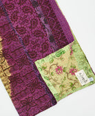 kantha quilt throw with a tag featuring the hand-stitched signature of the maker