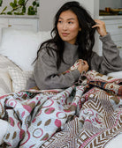 woman sitting on white sofa wrapped in red and white kantha blanket handmade in India