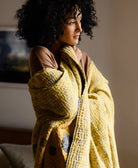 woman wrapped in goldenrod yellow kantha quilt handmade in India by Anchal's artisans