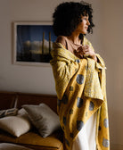 woman with mustard yellow kantha quilt draped around her shoulders