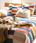 orange kantha blanket draped over rainbow checkered bedding in modern bedroom