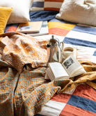 orange paisley kantha quilt draped over organic cotton patchwork bedding by Anchal