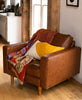 vintage kantha quilt by Anchal Project in warm leather armchair with mustard curve lumbar accent pillow