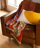 red kantha quilt throw ethically made in India from upcycled saris draped over brown leather armchair