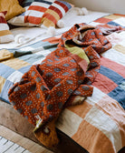 rust red kantha quilt draped over multi-colored checkered bedding in rustic modern bedroom