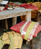 orange and yellow kantha quilts draped over outdoor picnic table wooden bench