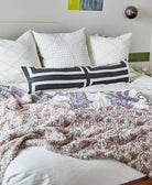 white and purple paisley kantha quilt draped over all white bedding in modern bedroom